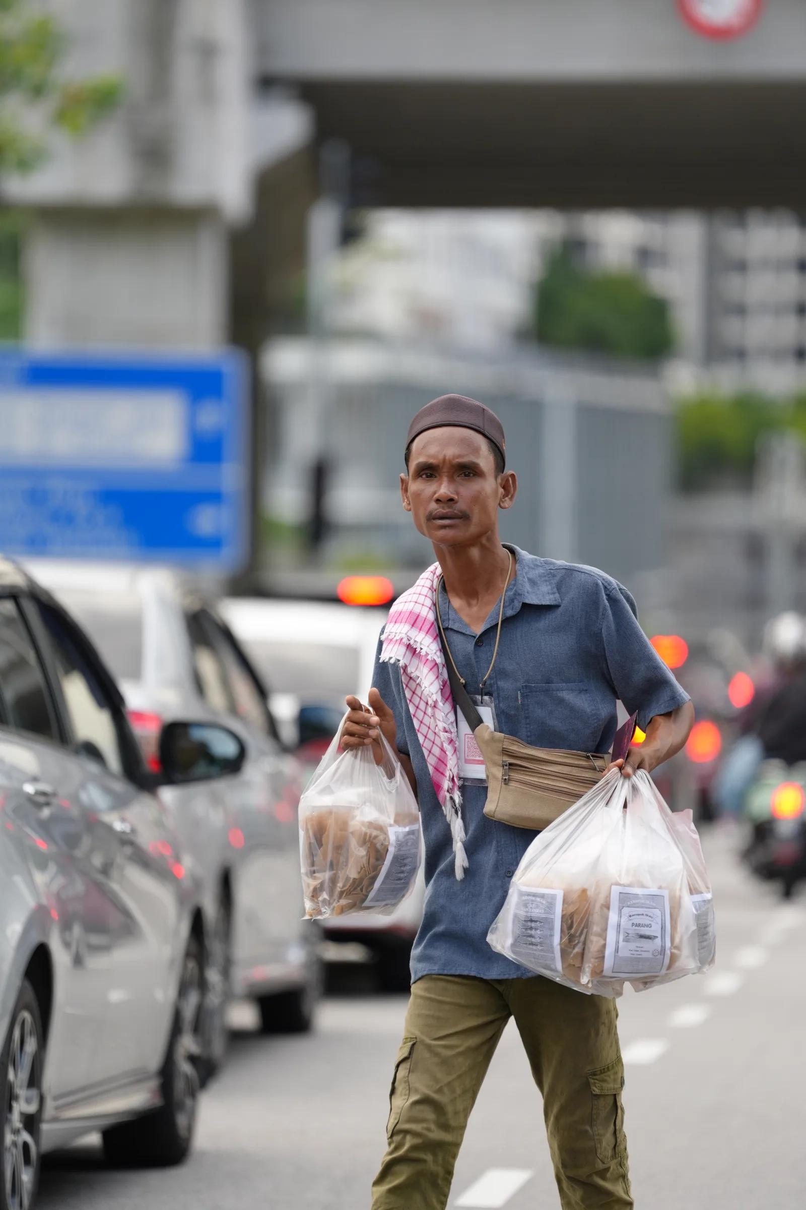 Man in songkok and keffiyeh carrying bags of iftar food — candid Ramadhan portrait
