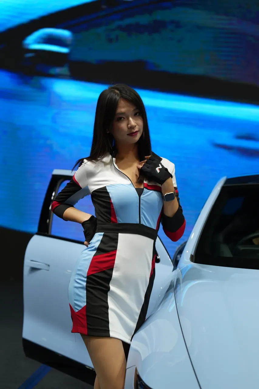 Racing-livery presenter beside a pickup under screen light