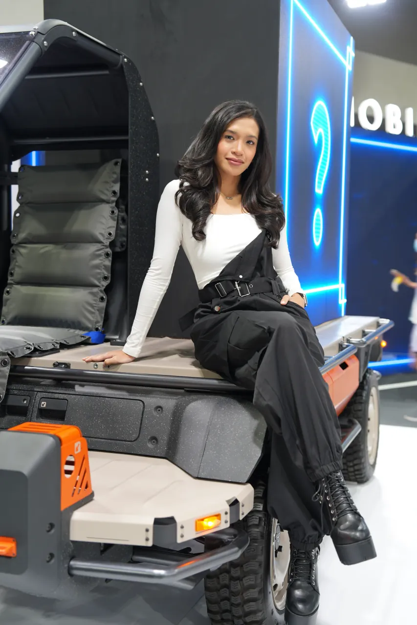 Product presenter seated on a compact utility vehicle under blue stage light