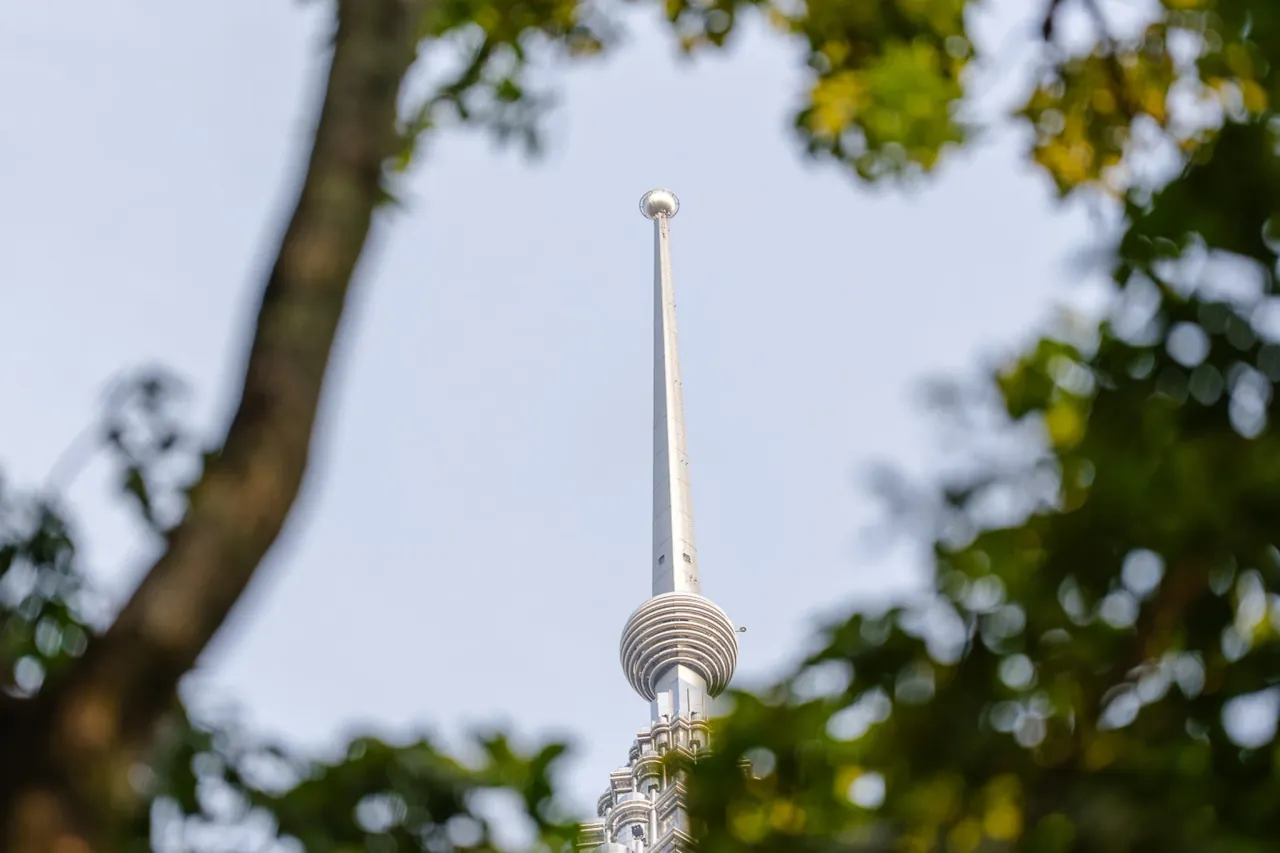Petronas Tower spire through the KLCC Park canopy — architecture meets nature