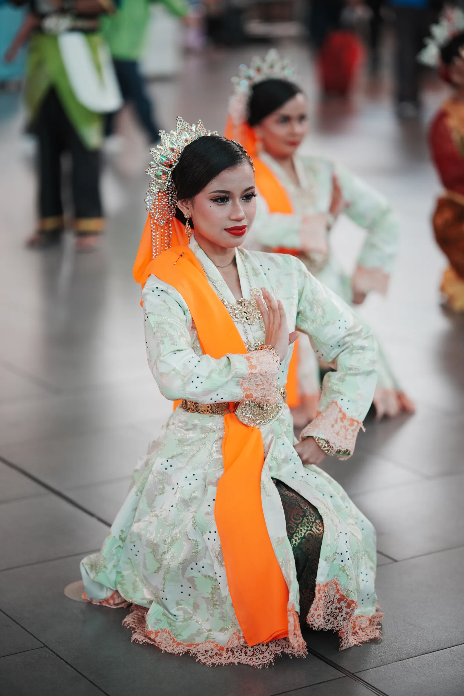 Kneeling dance pose with traditional hand gesture — cultural event photography