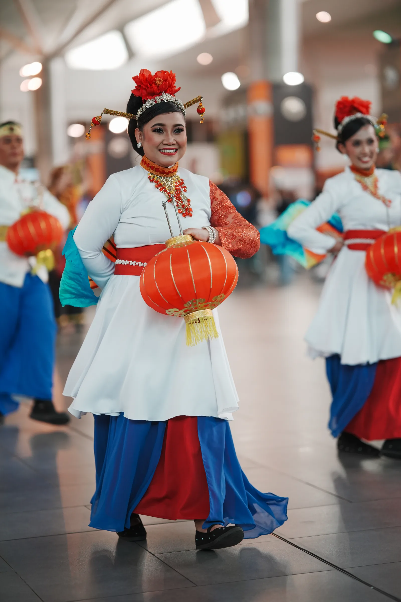 Three dancers in formation with red lanterns — Malaysian cultural event