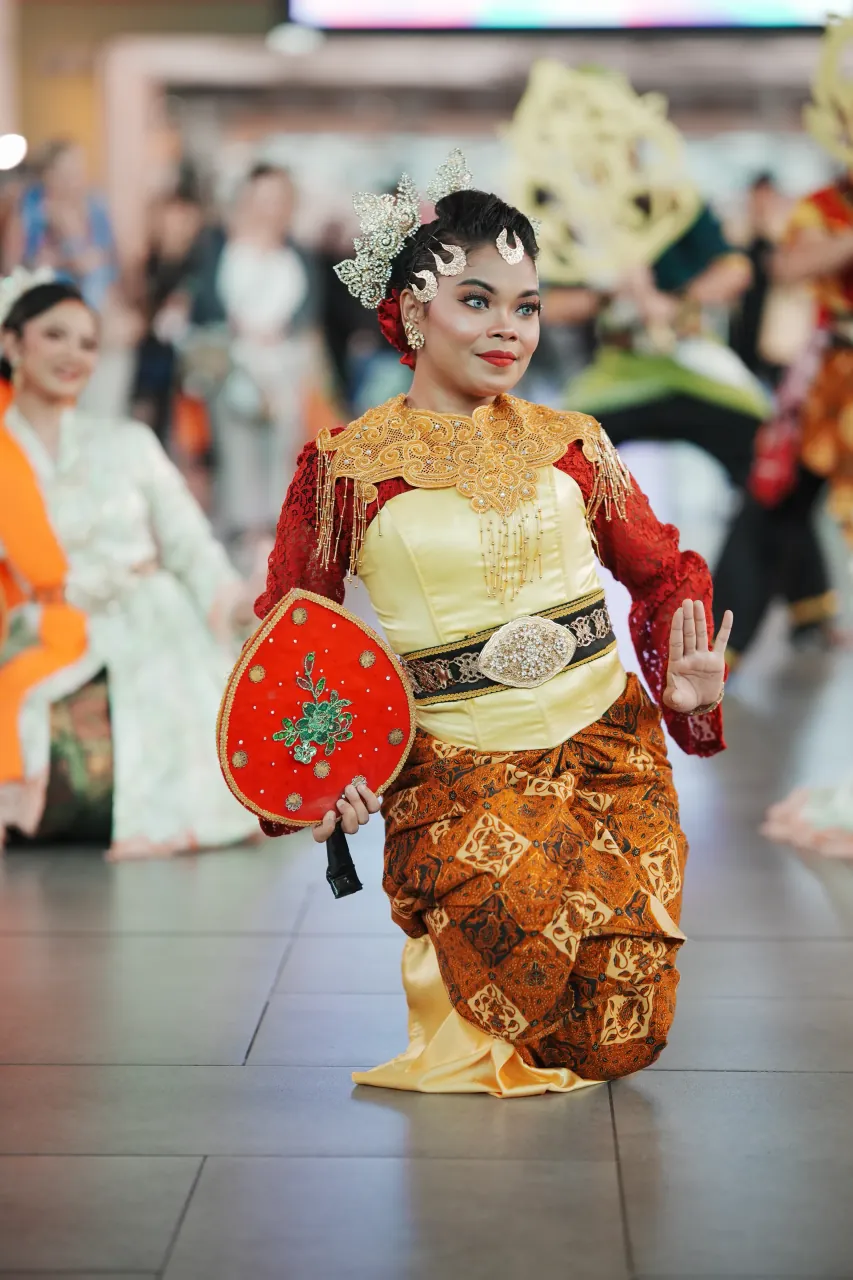 Javanese-style dancer kneeling with decorative fan prop